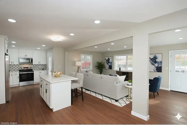 a living room with stainless steel appliances kitchen island furniture and a wooden floor