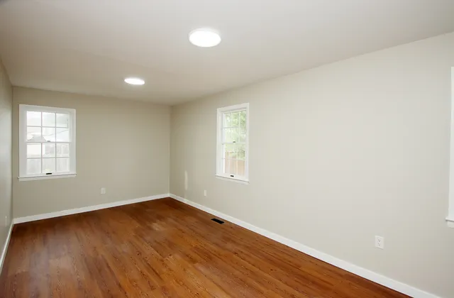 an empty room with wooden floor and windows