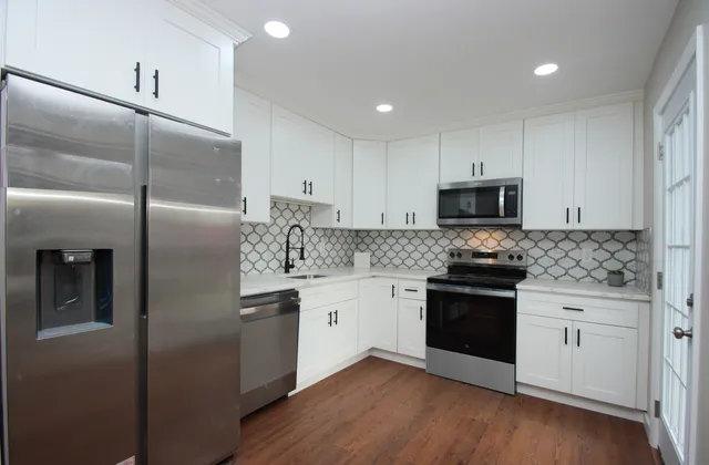 a kitchen with granite countertop white cabinets and stainless steel appliances