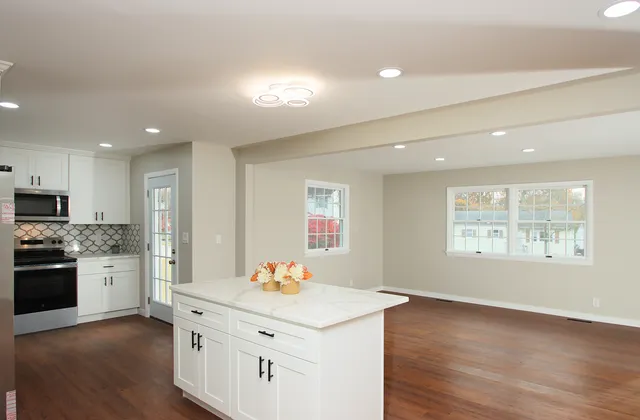 a kitchen with stainless steel appliances kitchen island granite countertop a stove a sink a refrigerator and white cabinets with wooden floor