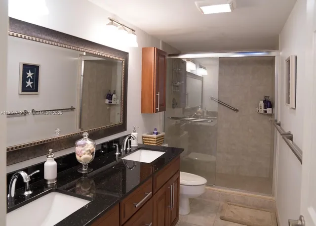 a bathroom with a double vanity sink toilet mirror and shower