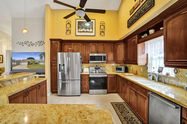 a kitchen with stainless steel appliances kitchen island granite countertop a refrigerator and a stove top oven