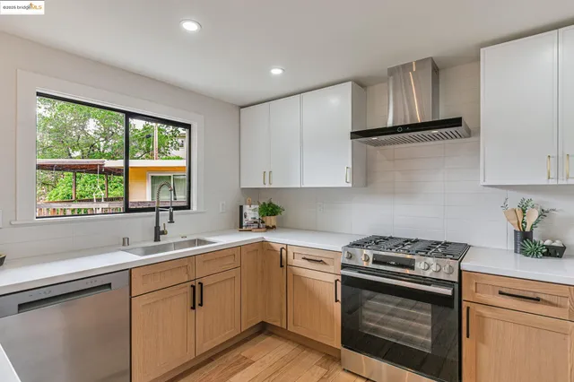 a kitchen with white cabinets appliances a sink and a window