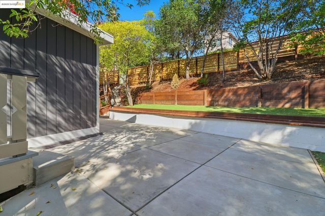 a view of backyard with wooden fence and large trees