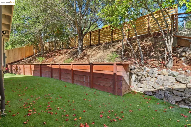 a view of backyard with wooden fence and a bench