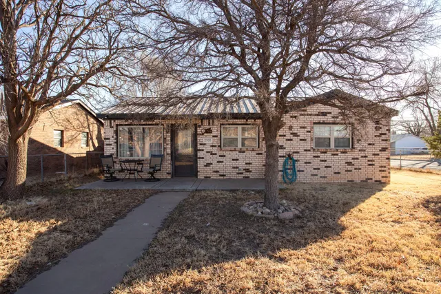 a large tree in front of a brick house