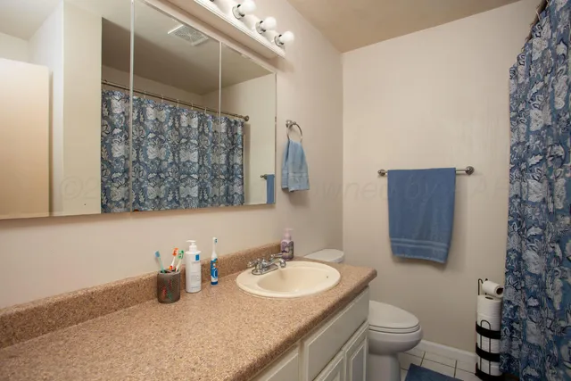 a bathroom with a granite countertop sink and a toilet