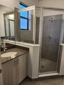 a bathroom with a granite countertop sink a mirror and shower