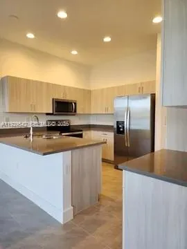 a kitchen with stainless steel appliances a refrigerator a stove a sink a microwave and island