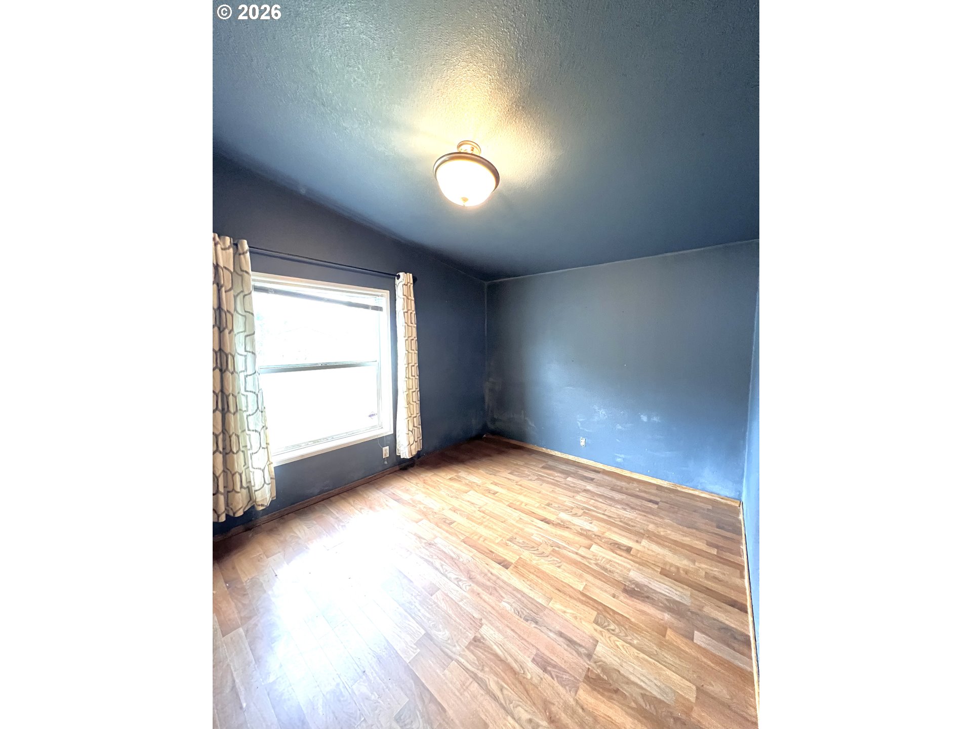 5200 Southeast 132nd Avenue, Unit 14 Portland, OR 97236 - Photo 12 of 17 a view of an empty room with a window and wooden floor