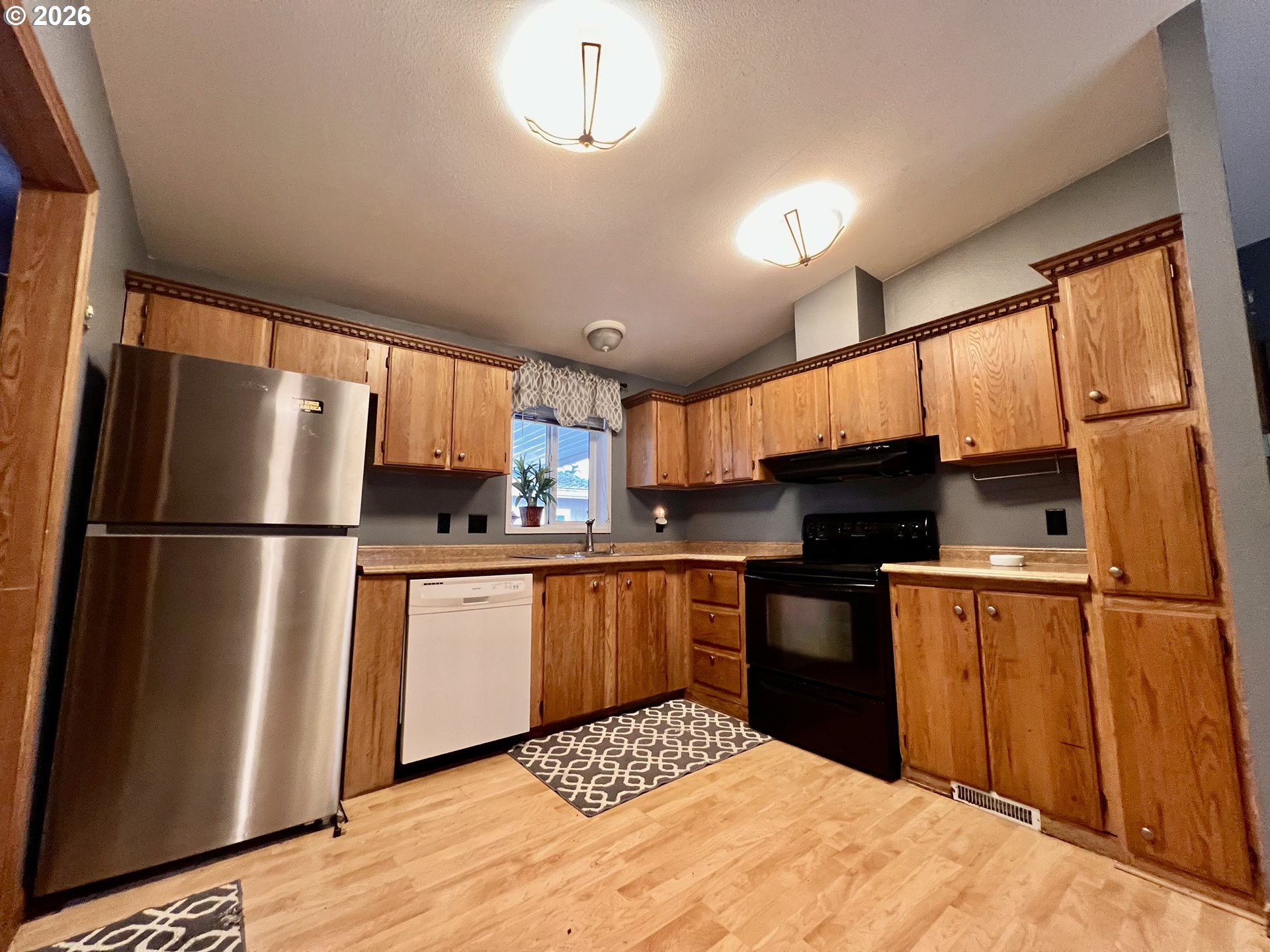 5200 Southeast 132nd Avenue, Unit 14 Portland, OR 97236 - Photo 5 of 17 a kitchen with stainless steel appliances granite countertop a refrigerator a sink dishwasher a stove and white countertops with wooden floor