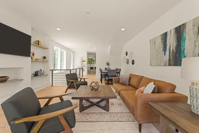 a living room with furniture a flat screen tv and a refrigerator