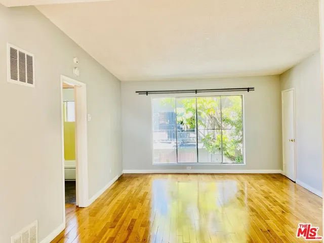a view of an empty room with a window and a kitchen