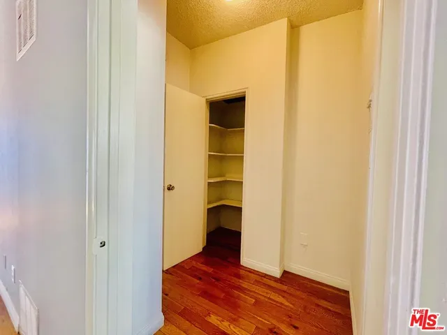 a view of an empty room with wooden floor and closet