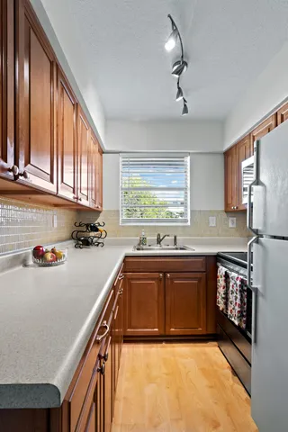 a kitchen with stainless steel appliances granite countertop a sink dishwasher stove and refrigerator with wooden floor