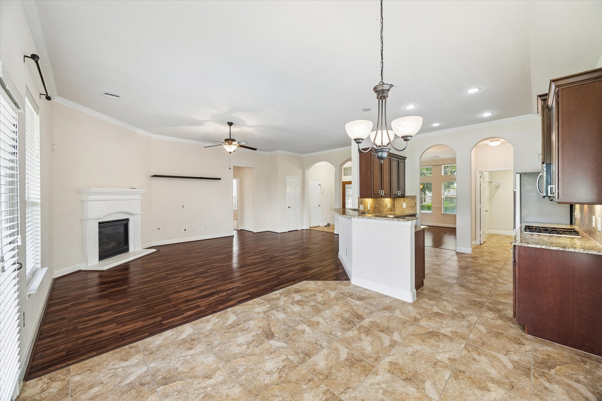 2214 Wembley Way Rosenberg, TX 77471 - Photo 20 of 35 Living area and kitchen featuring wood-finish flooring, tile flooring, a corner fireplace, arched doorways, and a breakfast bar with pendant lighting