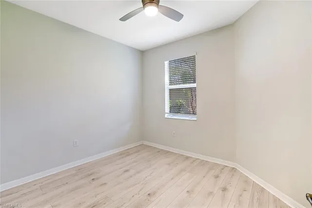 an empty room with a window and a ceiling fan