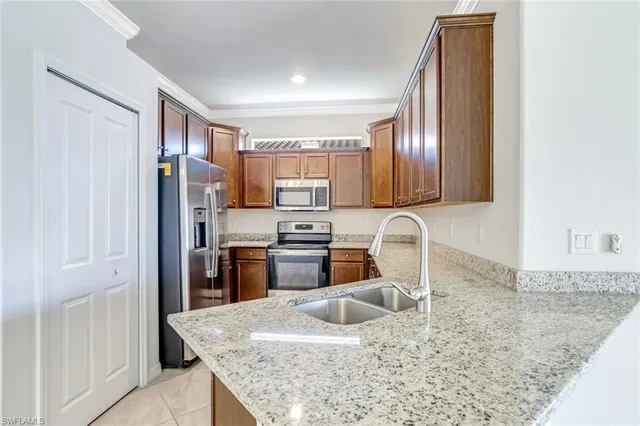 a kitchen with stainless steel appliances granite countertop a refrigerator a stove and a sink