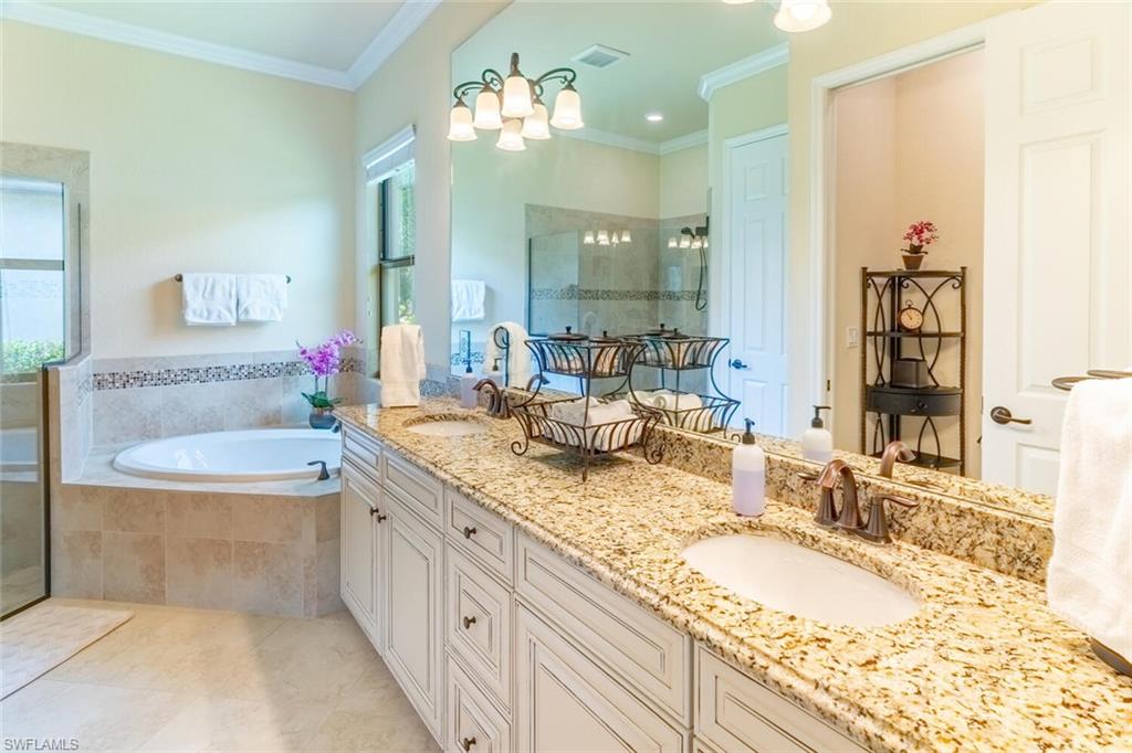 9372 Vercelli Court Naples, FL 34113 - Photo 22 of 50 Bathroom featuring tile patterned floors, a wealth of natural light, double sink vanity, and a relaxing tiled tub