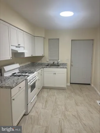 a kitchen with granite countertop a sink a stove and cabinets
