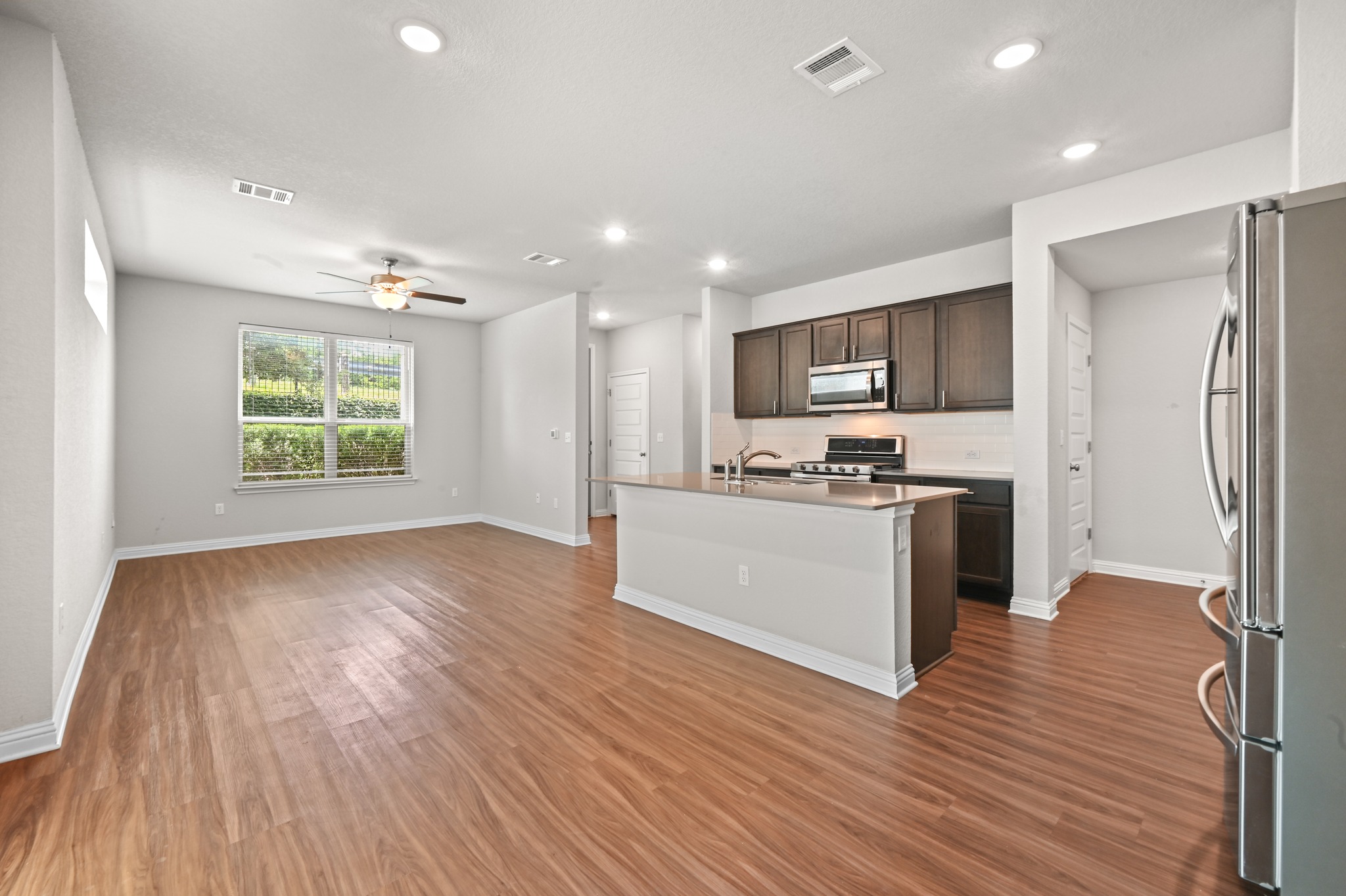 8201 Frida Bend Austin, TX 78744 - Photo 18 of 29 An open-concept layout showcases wood flooring and a contemporary kitchen with dark cabinetry.