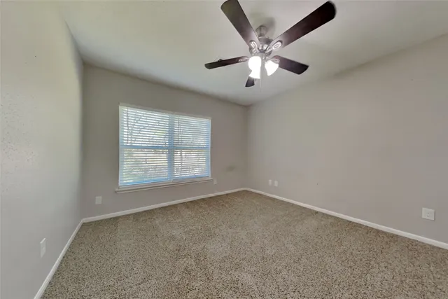 an empty room with a window and a fan