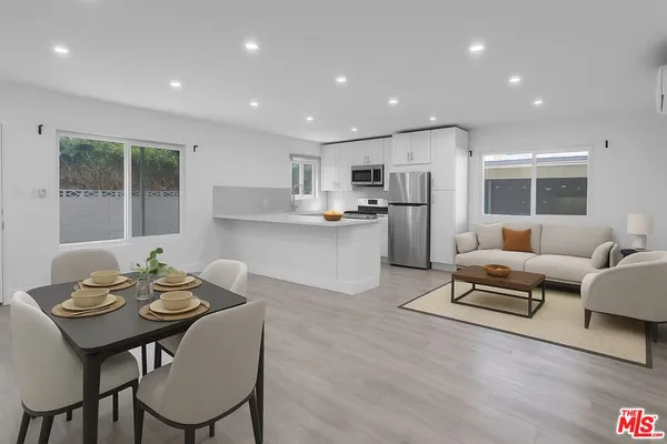 a living room with stainless steel appliances furniture and a dining table with wooden floor