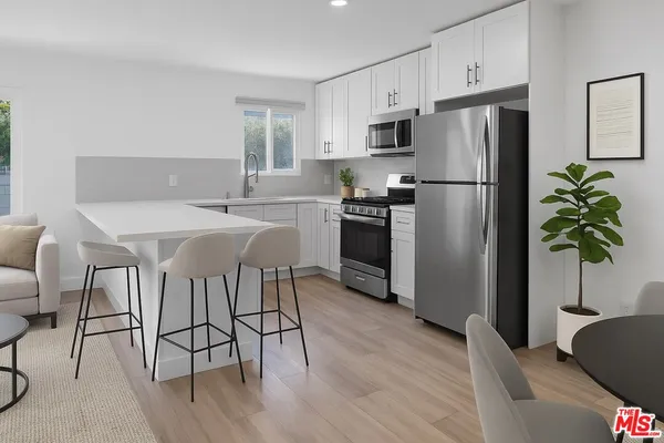 a kitchen with stainless steel appliances a refrigerator a stove a sink cabinets and a dining table