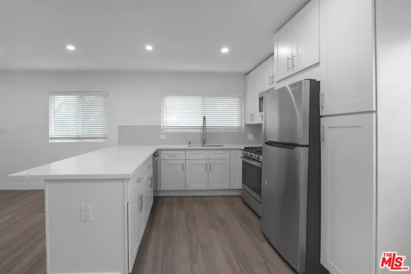 a kitchen with a refrigerator a sink and dishwasher with wooden floor