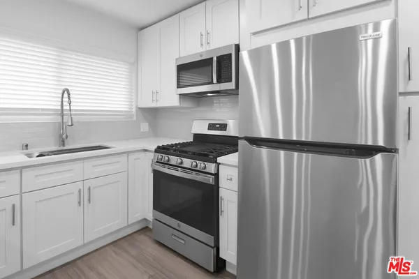 a kitchen with stainless steel appliances a stove microwave and sink