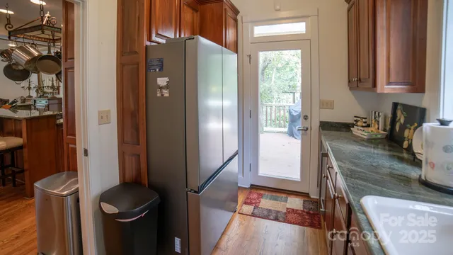 a kitchen with stainless steel appliances granite countertop a refrigerator a stove and a sink with wooden floor