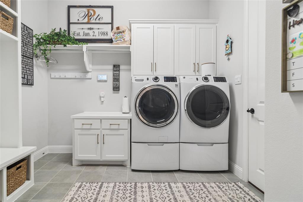1920 Lotus Court Haslet, TX 76052 - Photo 19 of 40 Large laundry room offers hanging for clothing, built in cabinets, folding table, cubbies with storage above and below. Door to 2nd 2 car garage for ease of unloading groceries.