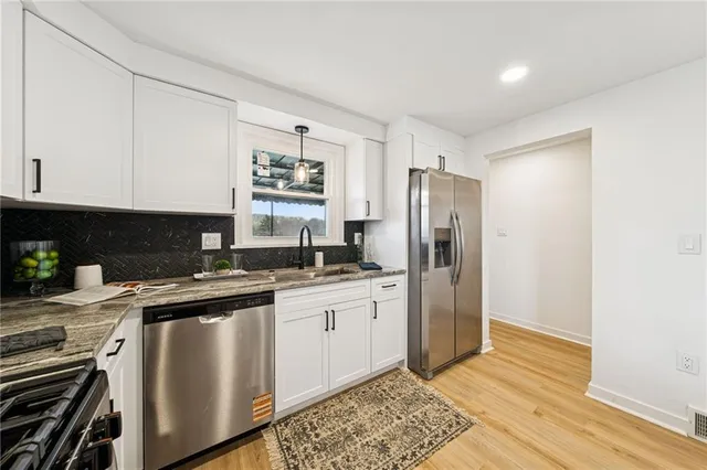 a kitchen with stainless steel appliances white cabinets and a refrigerator
