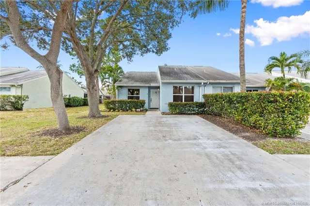 a front view of a house with a yard and potted plants