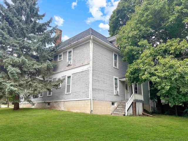 a front view of house with a garden and trees