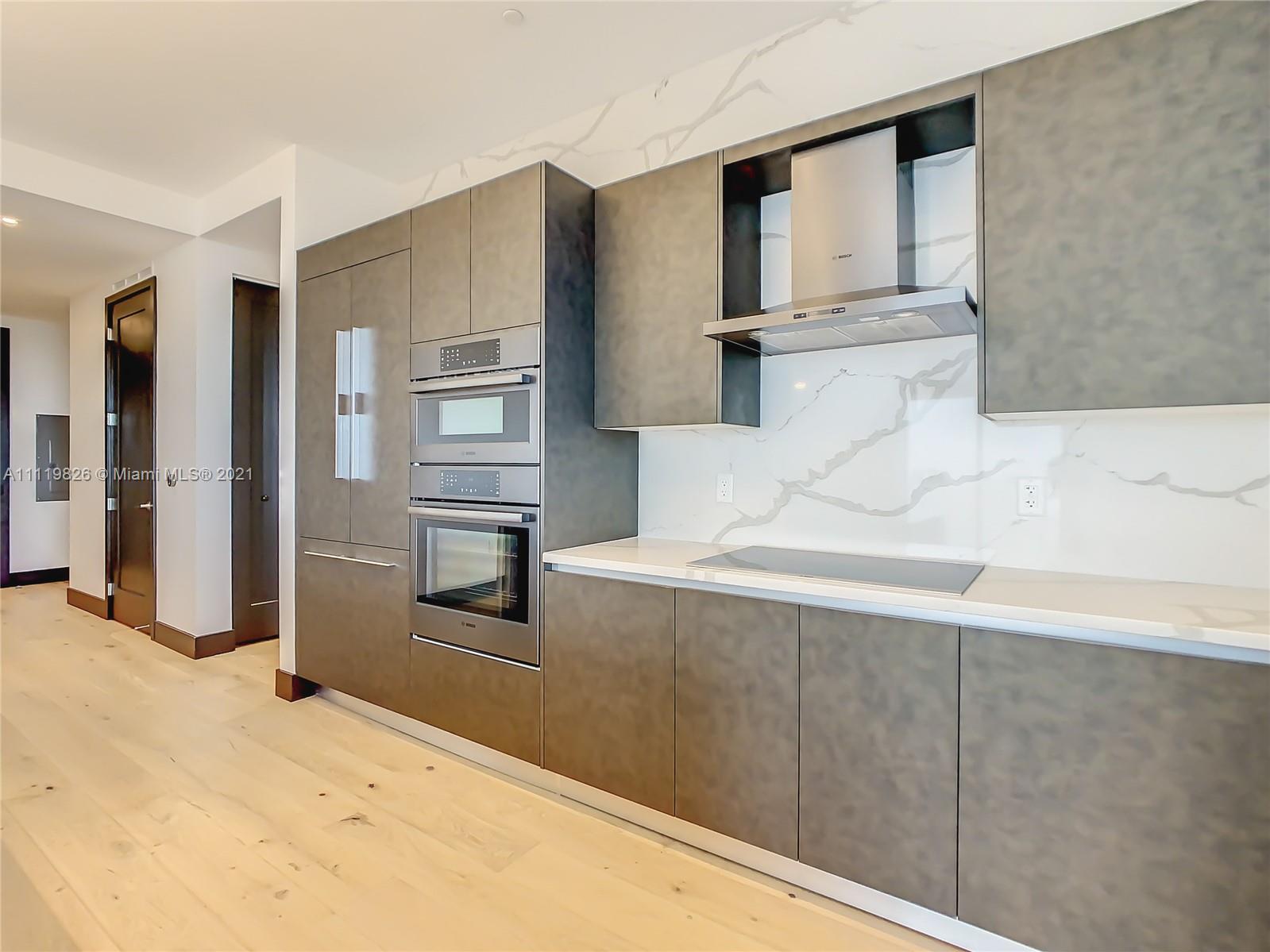 340 Southeast 3rd Street, Unit PH2 Miami, FL 33131 - Photo 12 of 54 a kitchen with kitchen island cabinets and stainless steel appliances