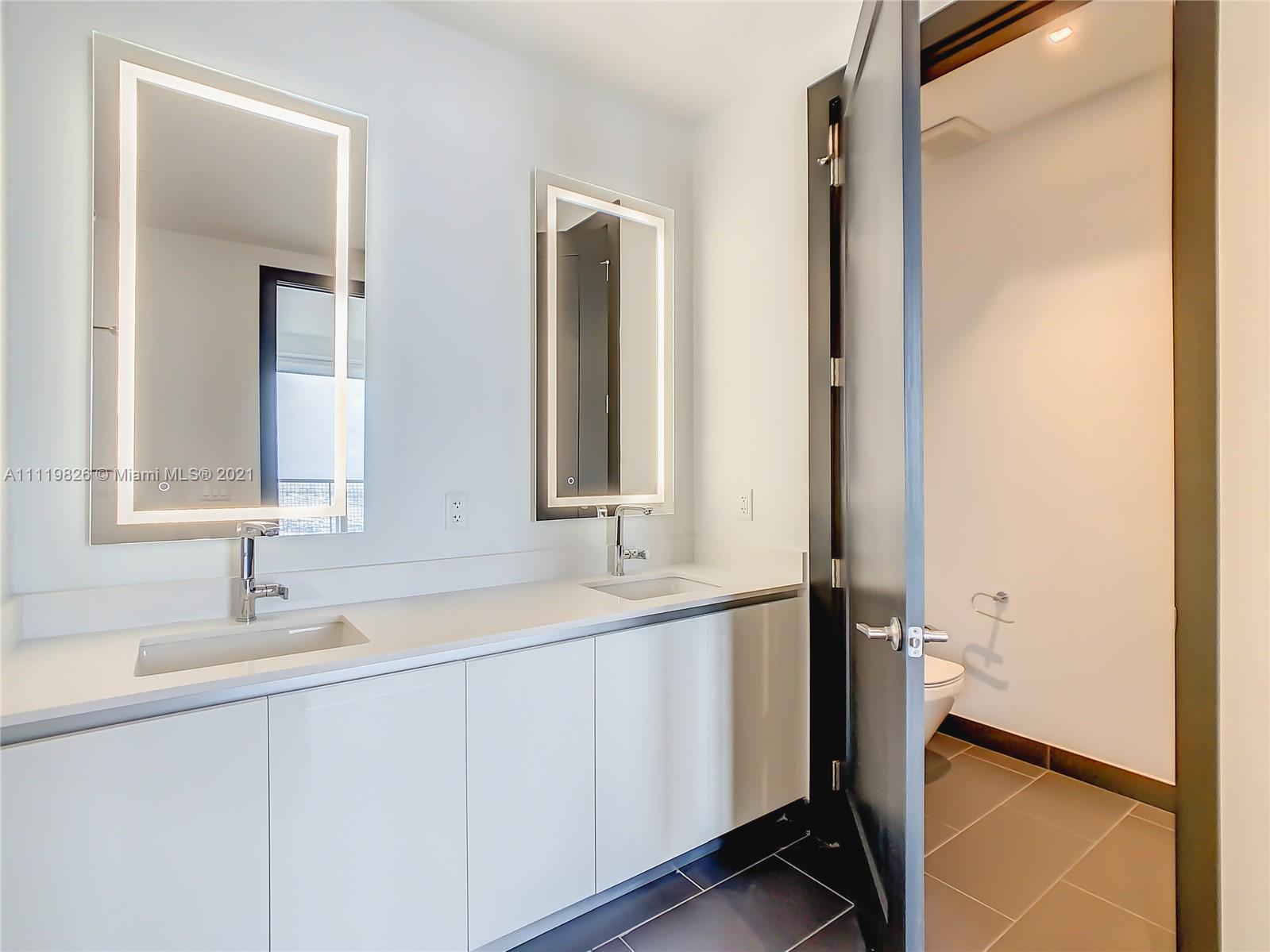 340 Southeast 3rd Street, Unit PH2 Miami, FL 33131 - Photo 20 of 54 a bathroom with a double vanity sink and mirror