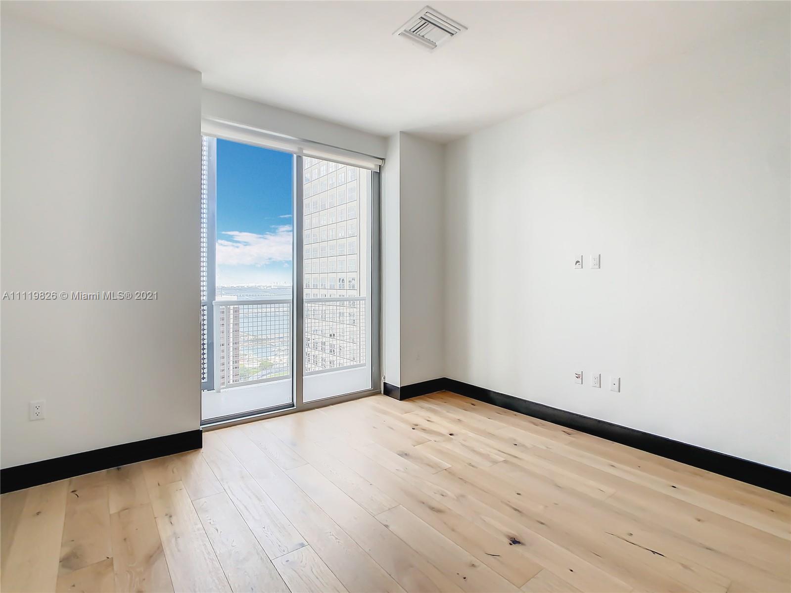 340 Southeast 3rd Street, Unit PH2 Miami, FL 33131 - Photo 23 of 54 an empty room with wooden floor and windows with curtains