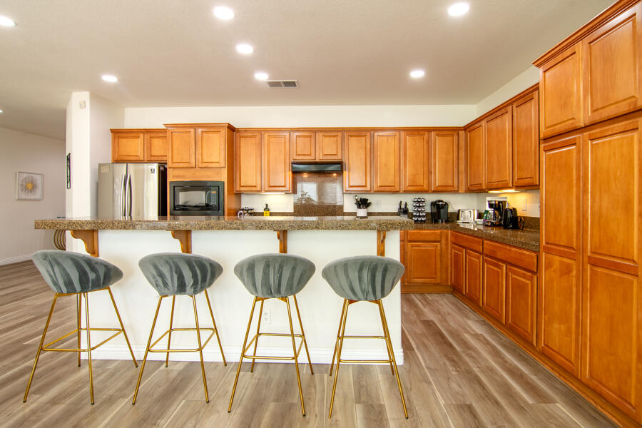 43784 Riunione Place Indio, CA 92203 - Photo 7 of 54 a kitchen with stainless steel appliances kitchen island granite countertop wooden floors and white cabinets