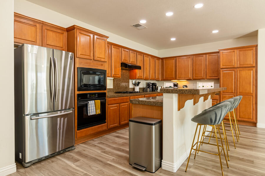 43784 Riunione Place Indio, CA 92203 - Photo 8 of 54 a kitchen with stainless steel appliances granite countertop a refrigerator a stove top oven and a refrigerator with wooden floor