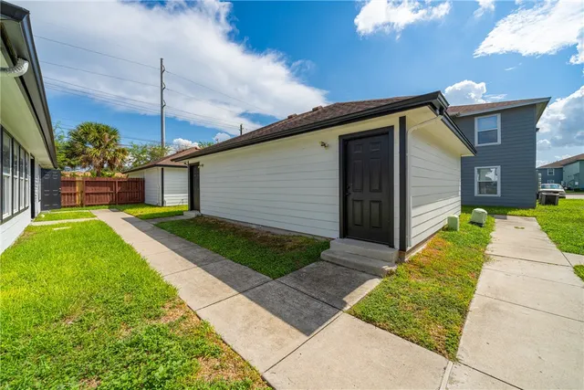 a front view of a house with a yard and potted plants