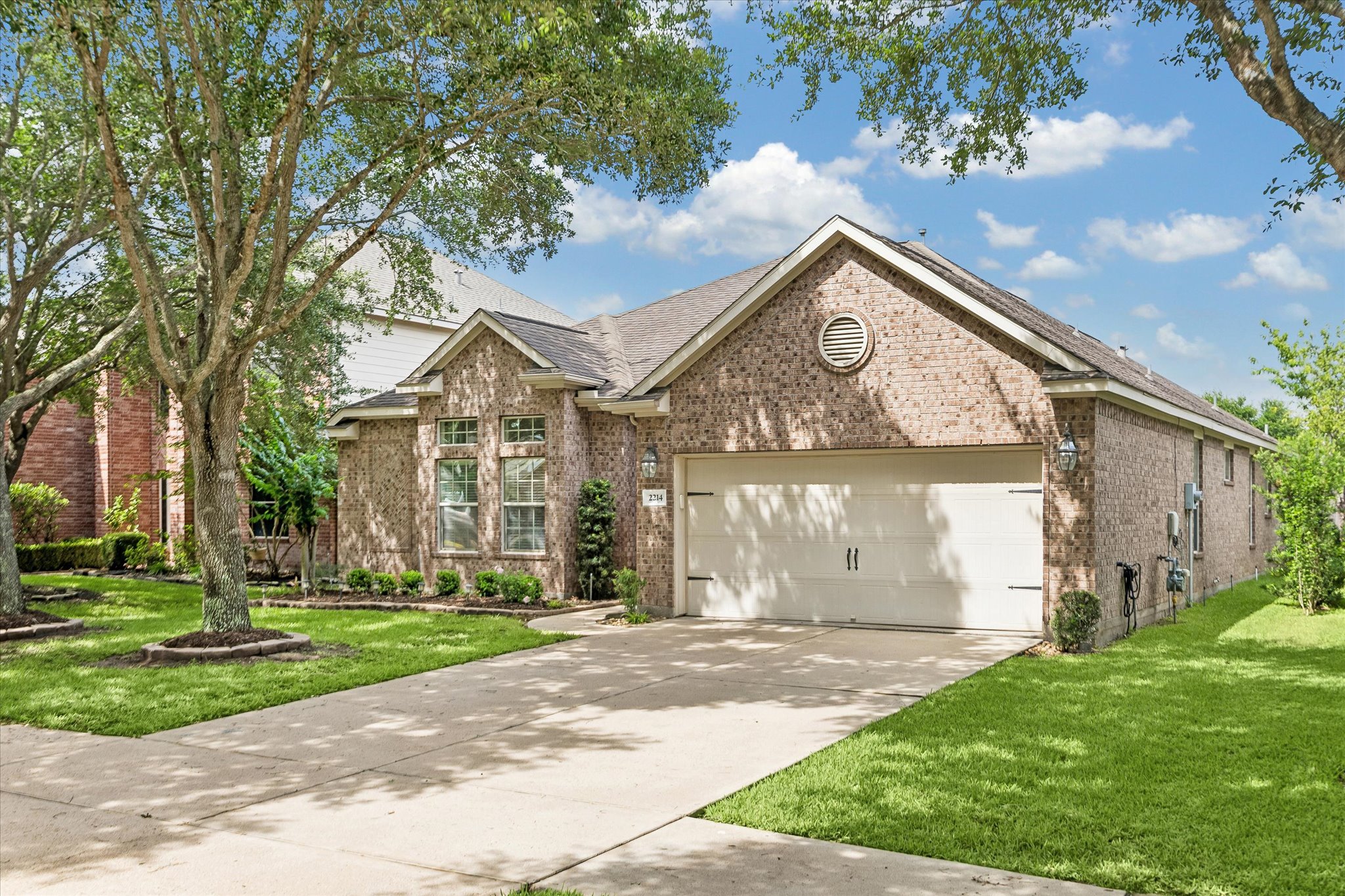 2214 Wembley Way Rosenberg, TX 77471 - Photo 2 of 35 Brick exterior residence featuring an attached two-car garage, concrete driveway, and mature landscaping