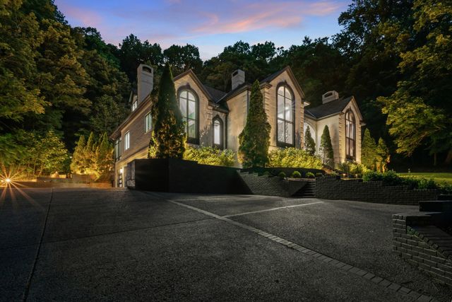 a front view of a house with a yard and tree s