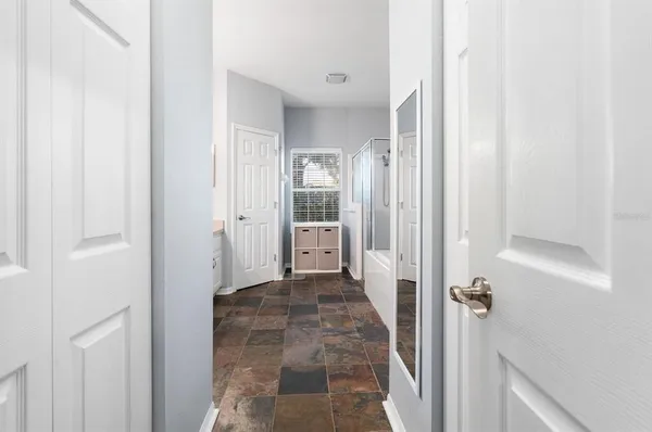 a view of a hallway with wooden floor and a bathroom