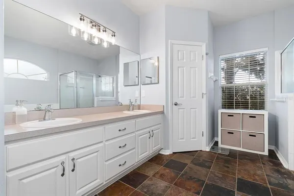 a spacious bathroom with a double vanity sink a mirror and a shower
