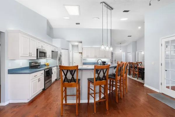 a kitchen with stainless steel appliances a dining table chairs stove and white cabinets