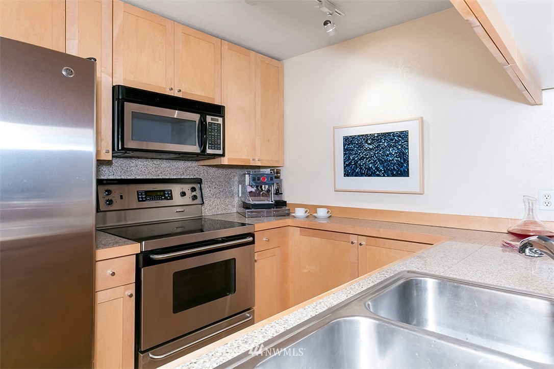 275 West Roy Street, Unit 319 Seattle, WA 98119 - Photo 3 of 18 a kitchen with stainless steel appliances granite countertop a stove microwave and sink