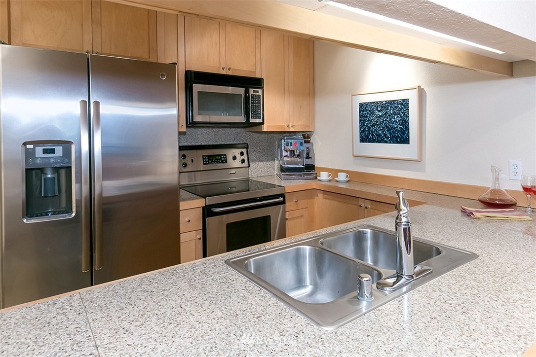 275 West Roy Street, Unit 319 Seattle, WA 98119 - Photo 5 of 18 a kitchen with stainless steel appliances granite countertop a sink a microwave a stove and refrigerator