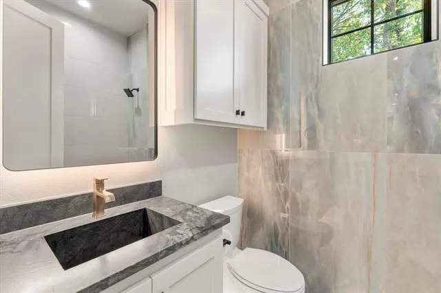 a bathroom with a granite countertop sink a toilet and shower