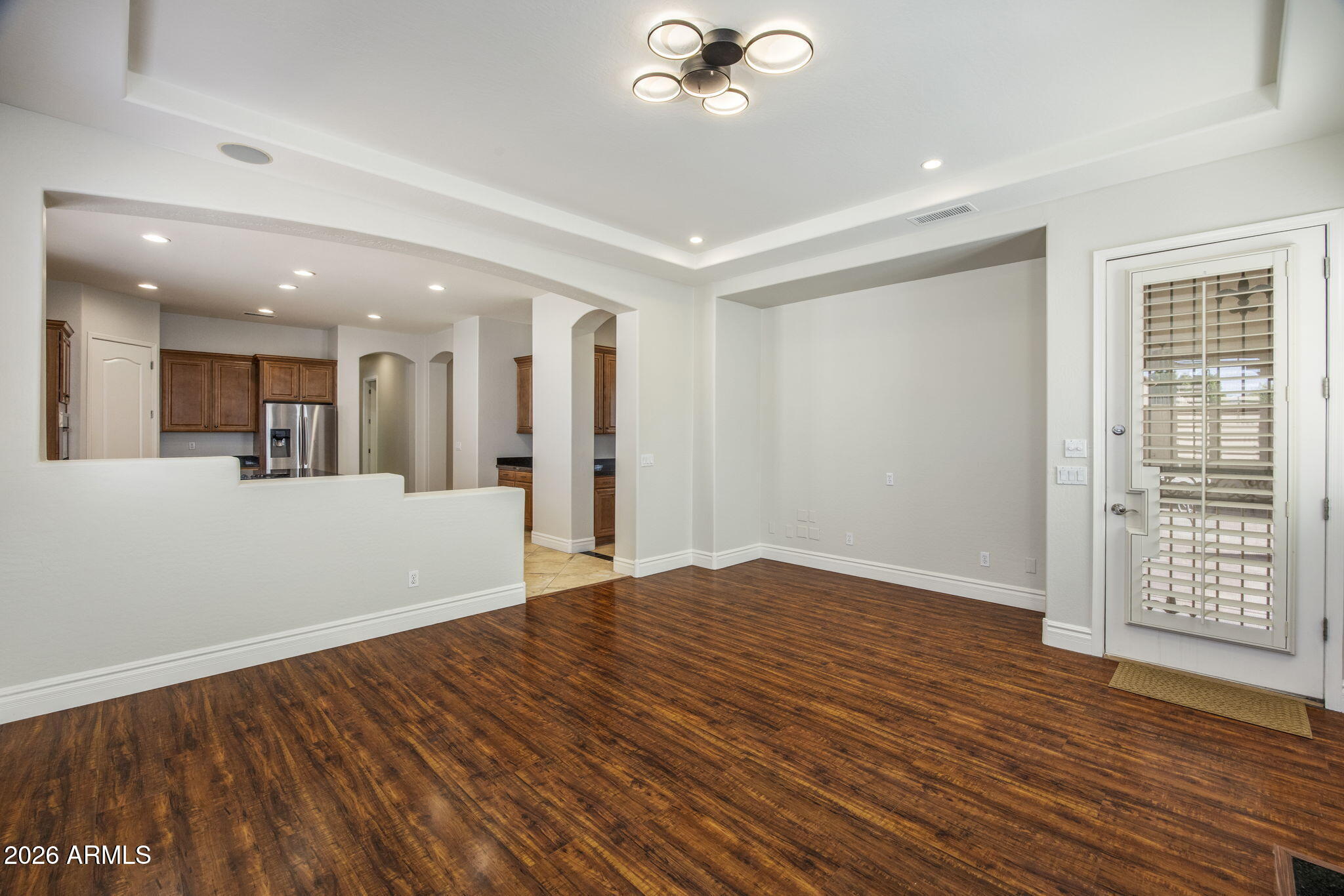 3215 East Constance Way Phoenix, AZ 85042 - Photo 14 of 40 a view of an empty room with wooden floor and a kitchen